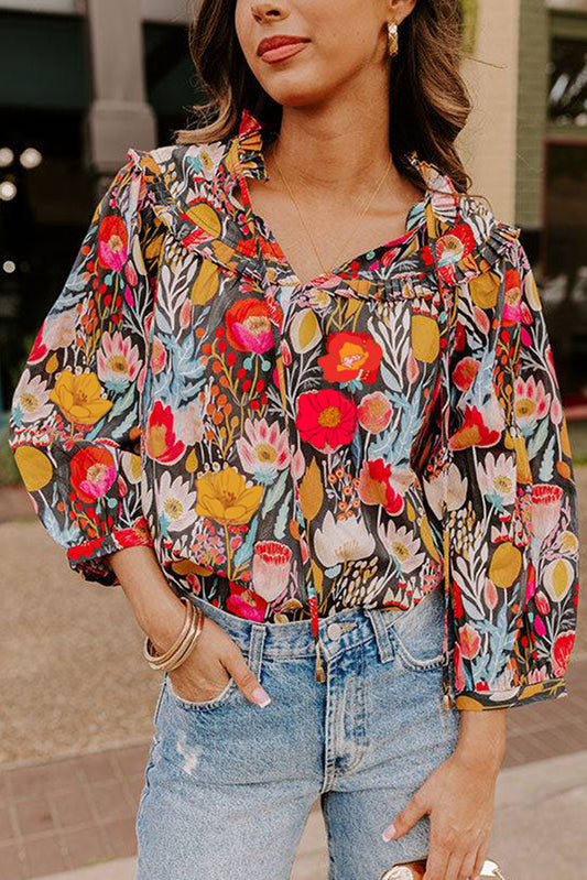 Blusa negra con estampado floral, mangas abullonadas 3/4 y cuello con volantes