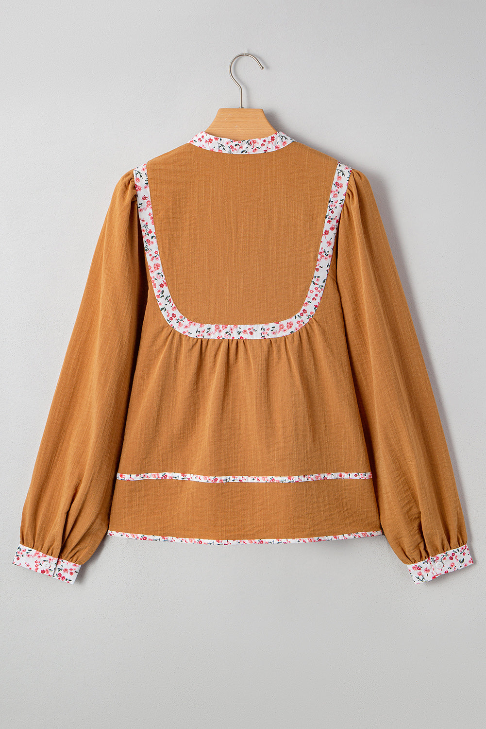 Blusa plisada con cuello abierto, ribete floral y mangas abullonadas de color amarillo paja
