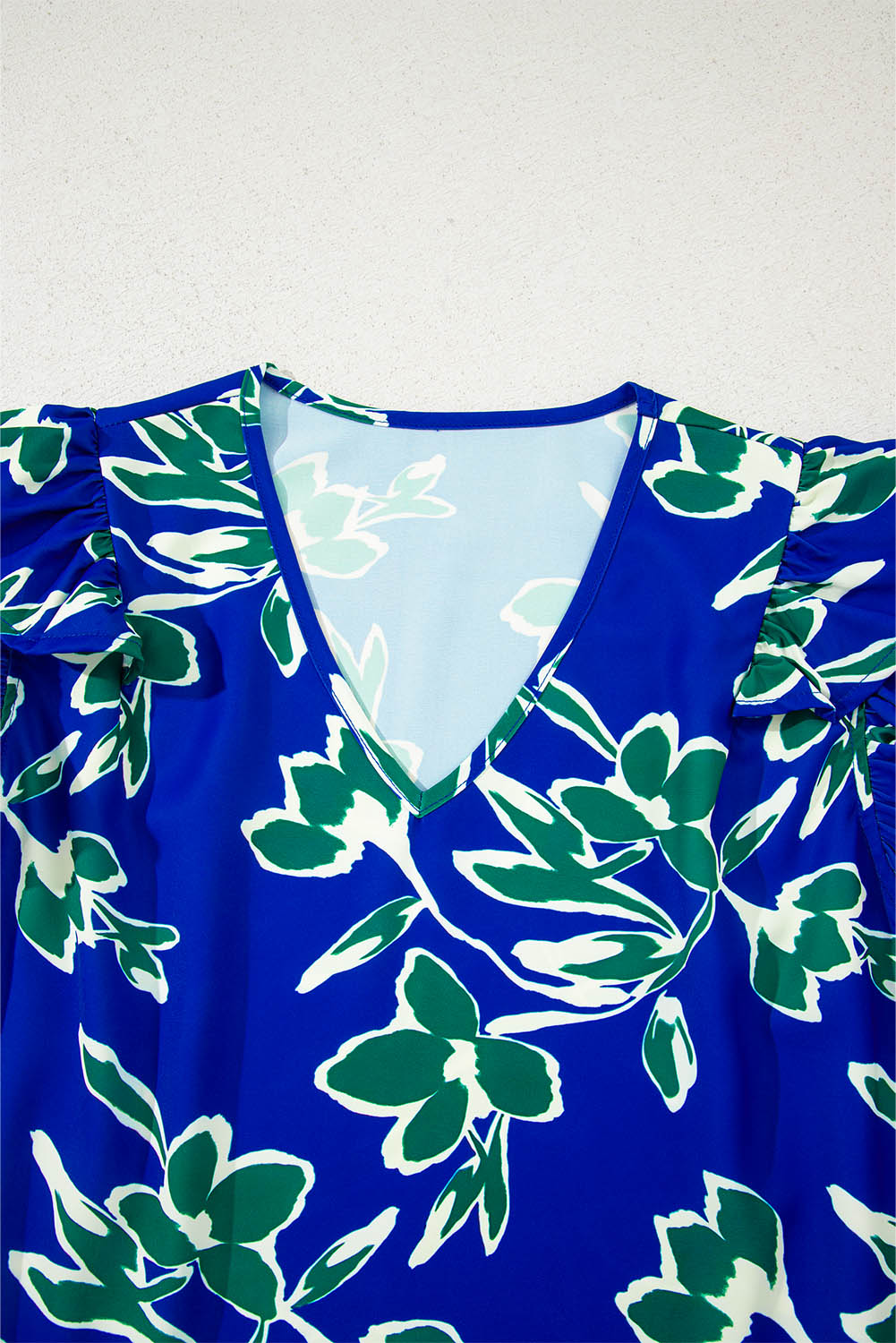 Blusa azul de manga corta con volantes, cuello en V y estampado floral