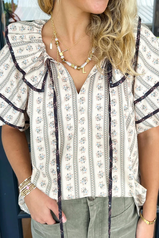Blusa blanca con estampado floral, cuello con volantes y mangas abullonadas cortas