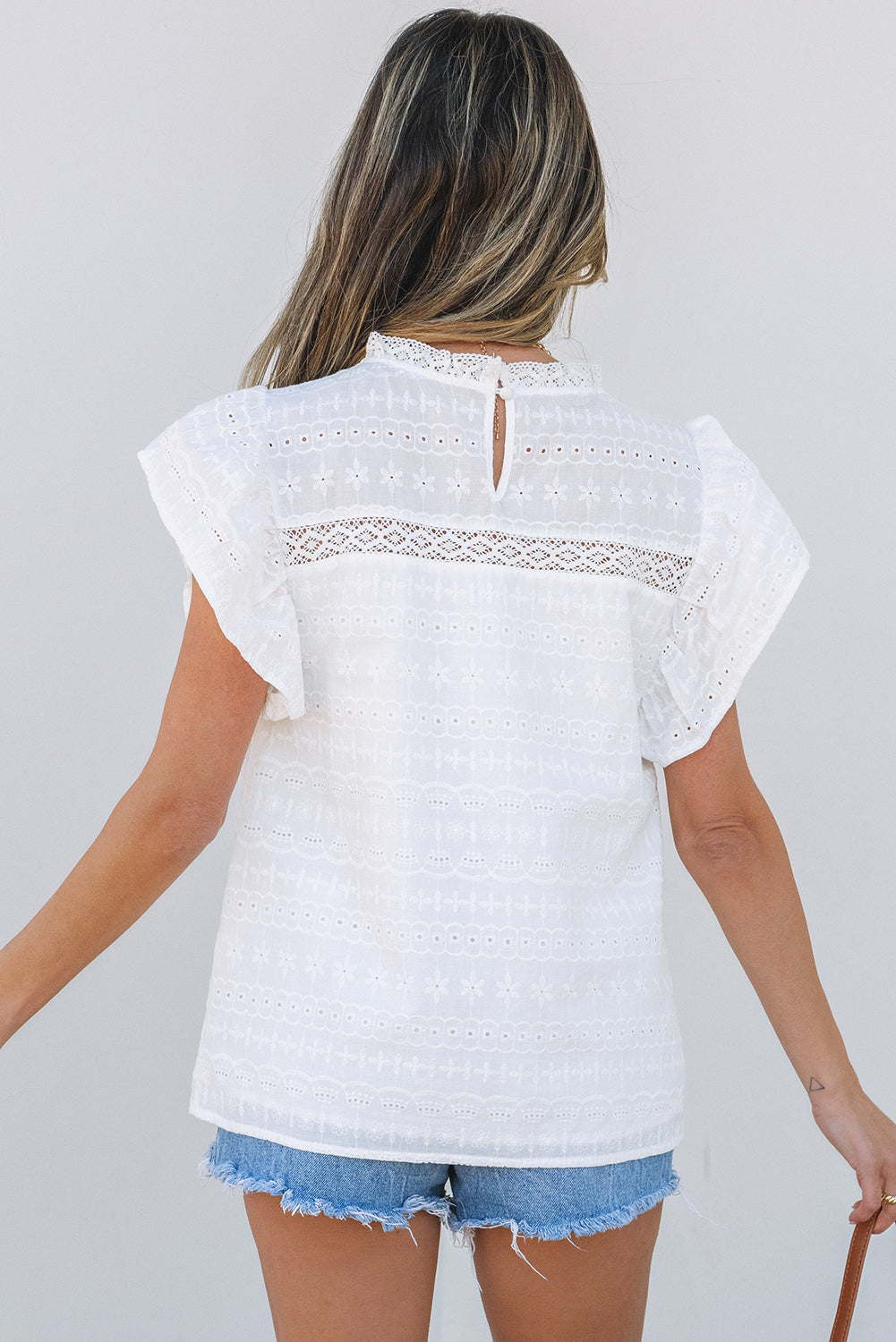 Blusa blanca con escote de encaje y mangas onduladas con ojales